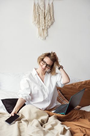 Woman Working From Home In Bed With Phone