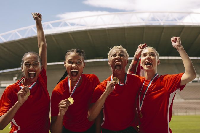 Woman soccer players with medals shouting in joy after winning the championship