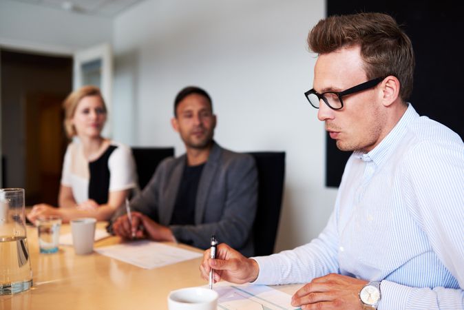 Man reading off paper in meeting with colleagues