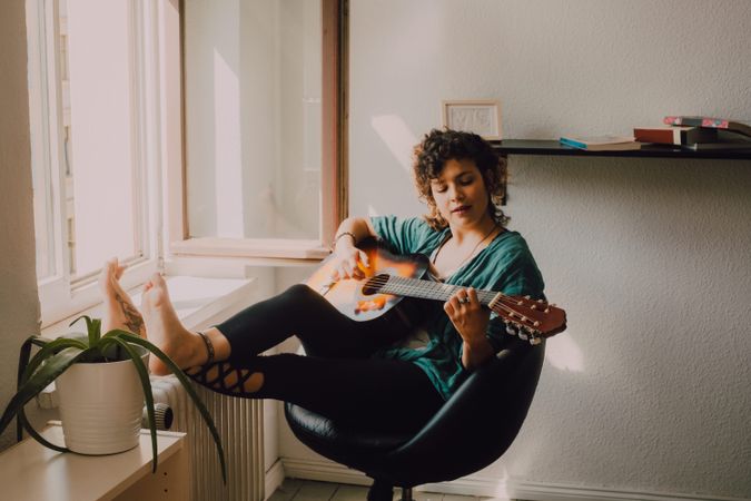 Content woman playing guitar at home