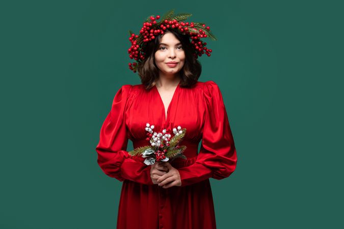 Woman wearing red gown and berry crown holding bouquet..
