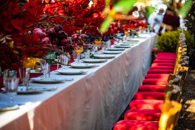 Elegant formal dinner table with red seats and red floral arrangements
