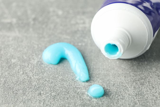 Question mark made of toothpaste and tube on gray background, closeup
