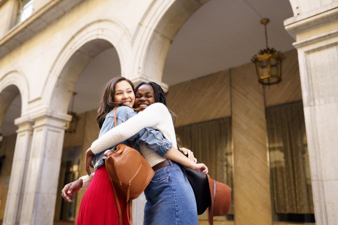 Female friends embracing each other on an outdoor street