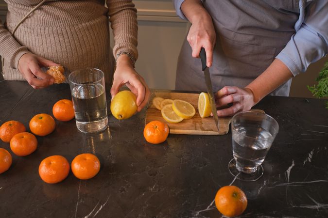 Crop women cutting fruits in kitchen