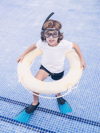 Boy with inflatable ring and snorkeling mask in pool