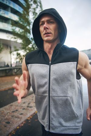 Intense man in vest jogging outside