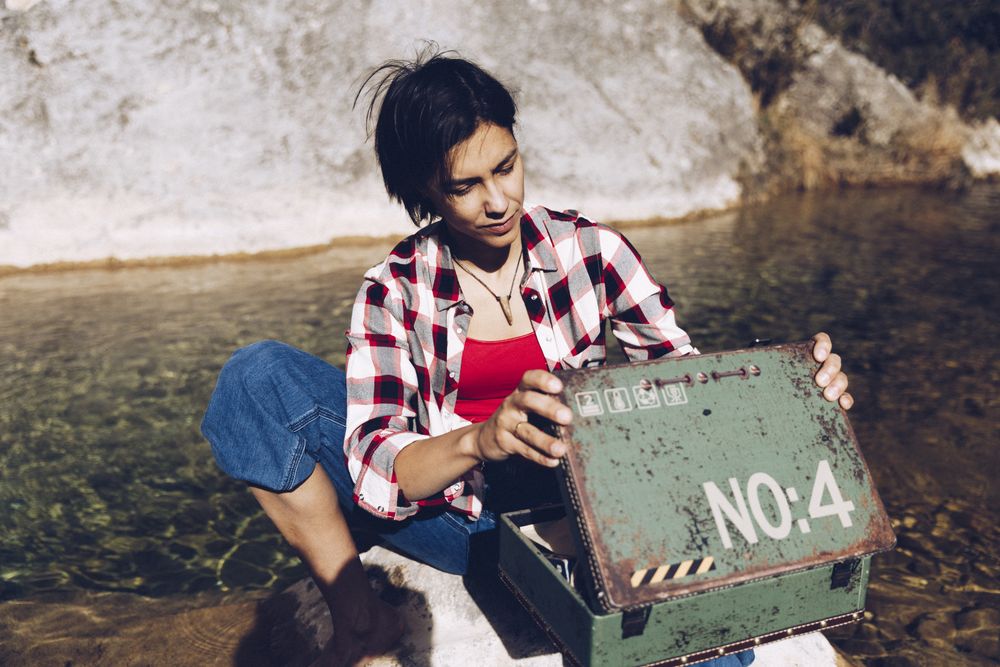 Woman with picnic case on rock in water