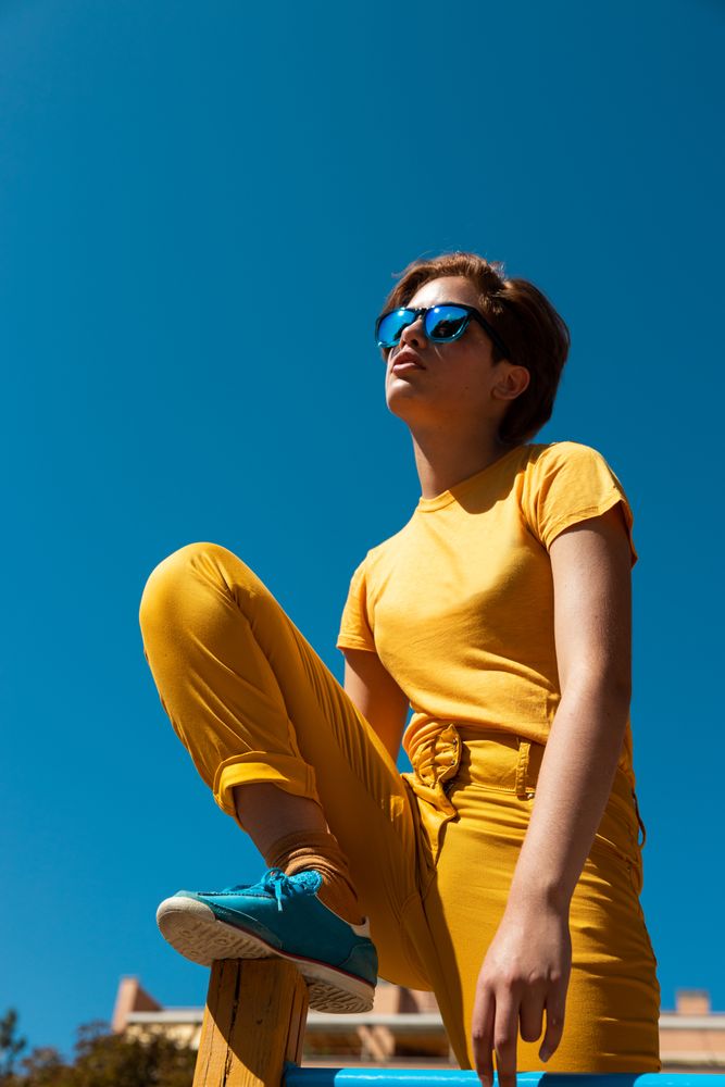 Cool stylish young woman in vibrant clothes on playground