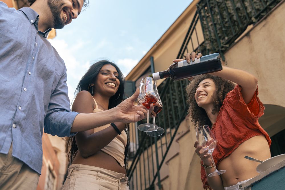 Group of young diverse friends laughing and pouring wine in a city.