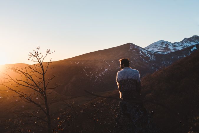 Female traveler sitting on mountain slope at sunset