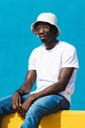Black man sitting on colorful wall