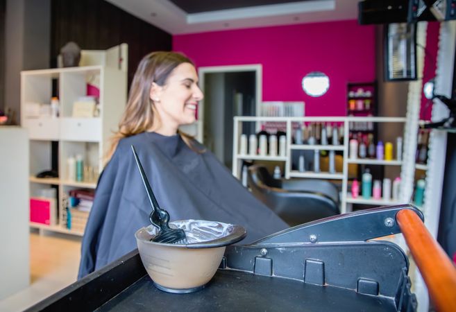 Smiling woman in salon chair awaiting having her hair dyed