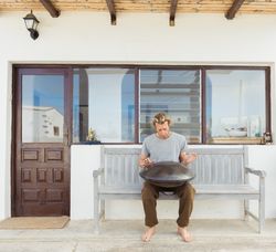 Blond man sitting on bench with big hand drum