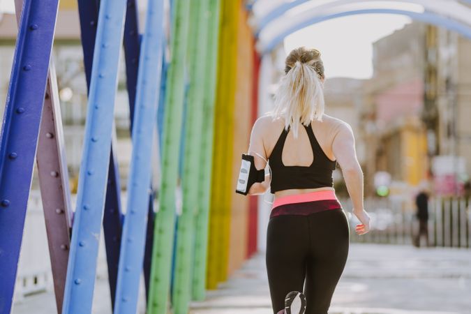 Woman with earphones running on street