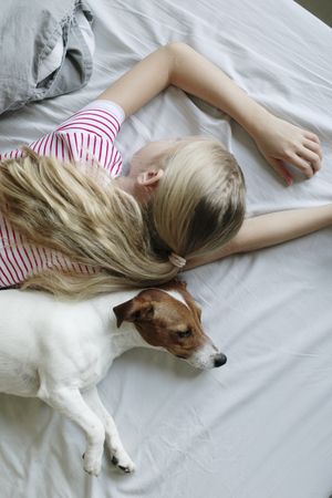 Top view of young girl lying on her stomach with her dog laying next to her