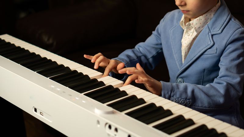 Side view of young boy playing digital piano