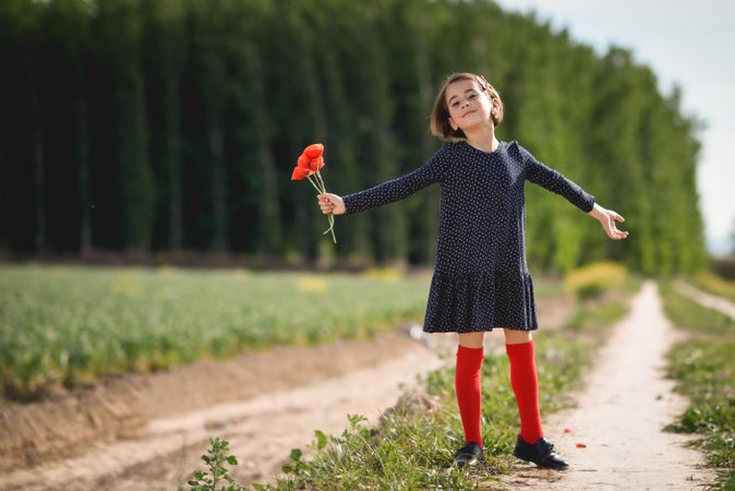 Girl posing for photo with red flowers in her hand