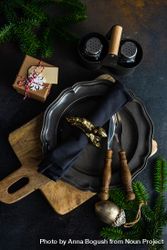 Top view of dark plate with knife and fork on table with pine and gifts bDrmK5