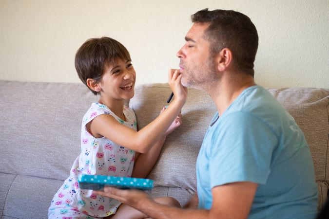 Child practicing make up on her dad