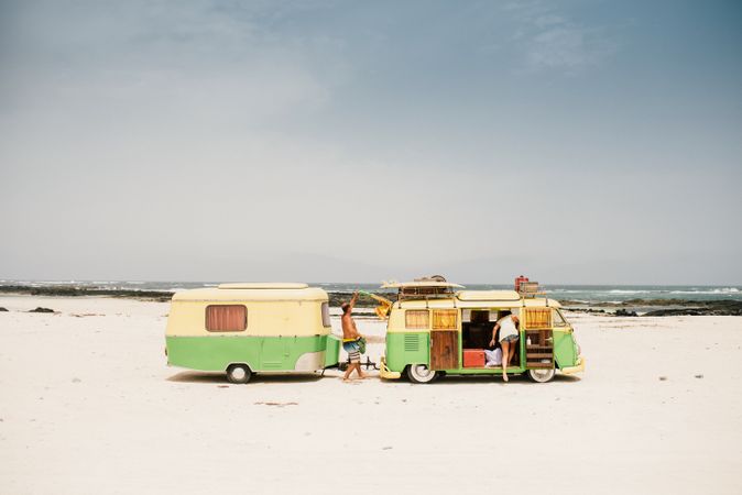 Friends in minibus with trailer on beach