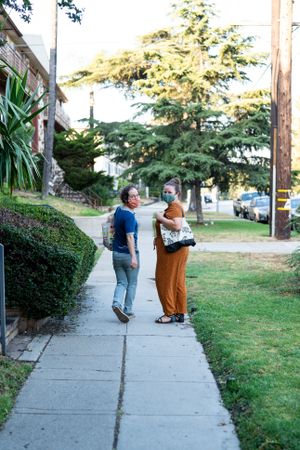 Man and woman walking away and looking back carrying grocery bags