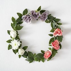 Pink and purple flowers and leaves in wreath on light background