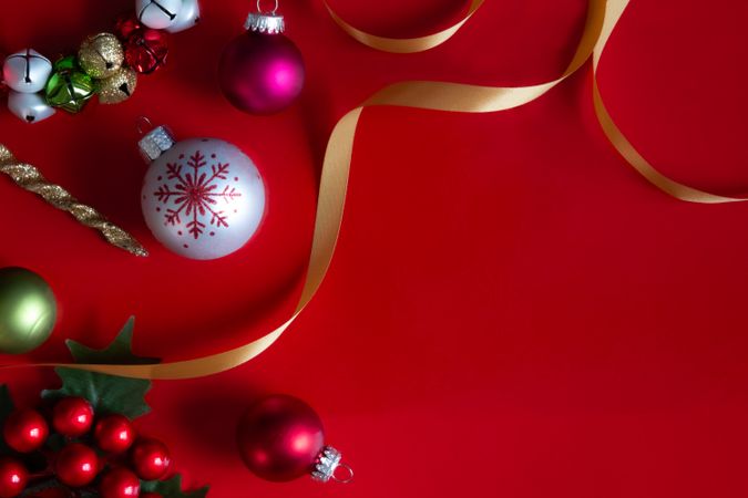 Red Christmas background with ribbons, ornaments, holly and bells.