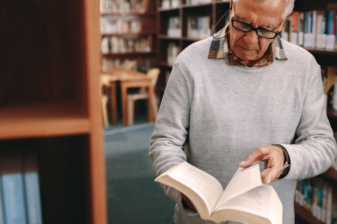 Older man checking for reference books in a university library
