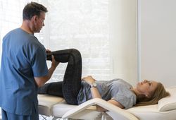 Physiotherapist working at woman's legs for wellness and disability support.