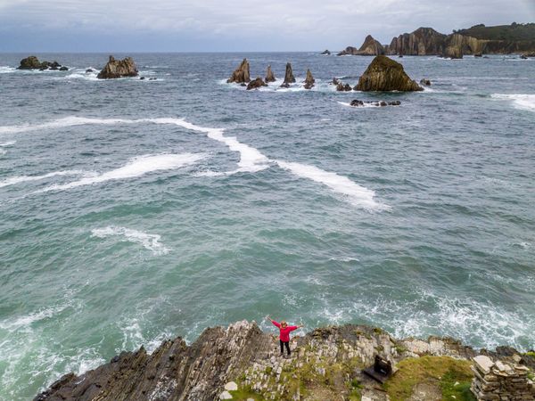 Woman standing on stony green seashore