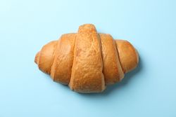Freshly baked croissant on blue background, top view