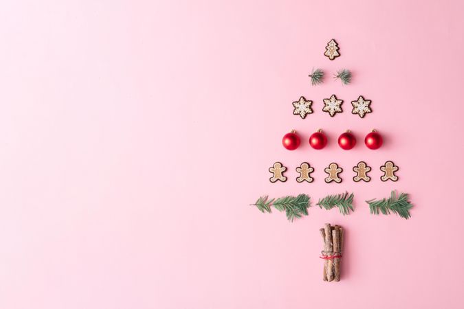 Christmas tree made with evergreen fir, bauble decoration and winter cookies on pink background