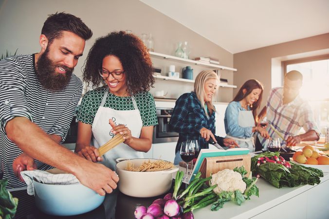 Group of happy friends cooking a pasta dinner