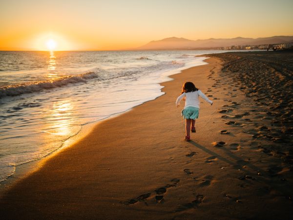 Cute little girl running on sand at beach