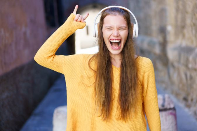 A Joyful Young Woman Dances While Listening to Music in a Bright and Vibrant Alleyway