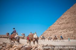 People riding camels on brown sand beside pyramid of Giza, El Omraniya, Giza Governorate, Egypt  4B7YPb