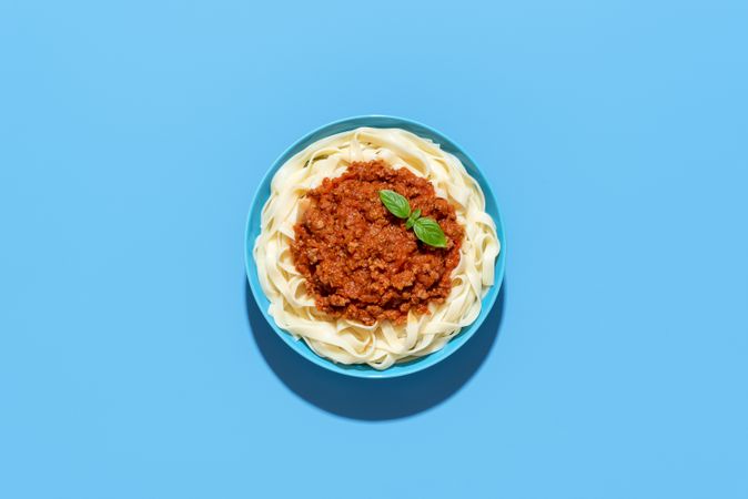 Bolognese tagliatelle dish top view, isolated on a blue background