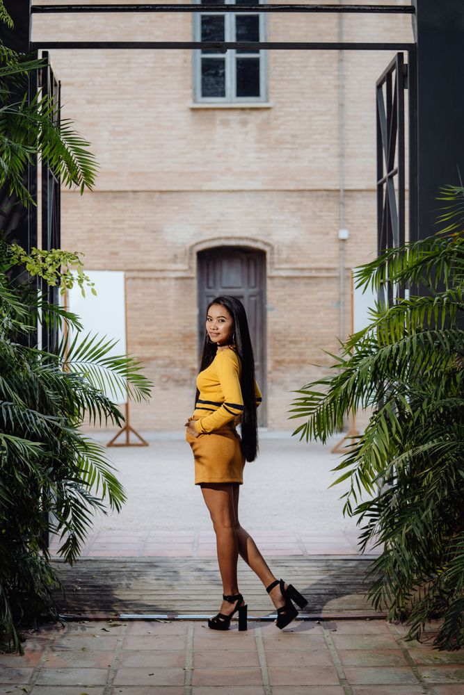 Glamour long haired Asian woman standing in metal arch on backgr