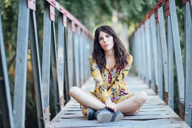 Female sitting cross legged on a rural bridge