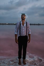 Man with fish tank on head standing at seashore