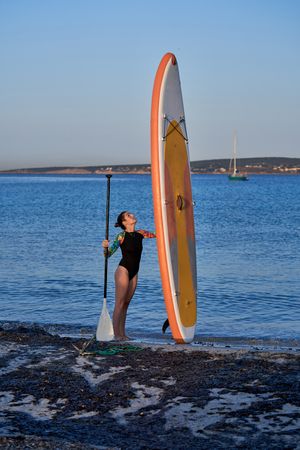 Woman standing with paddleboard on beach
