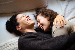 Two women lying down, laughing and embracing
