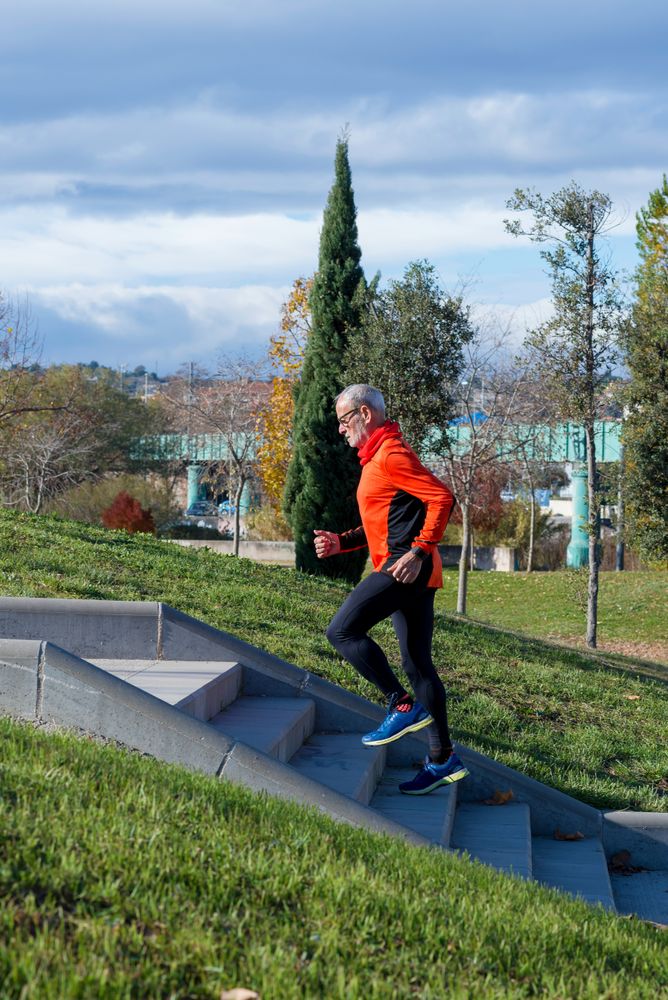 Side view of older male running up stairs in park