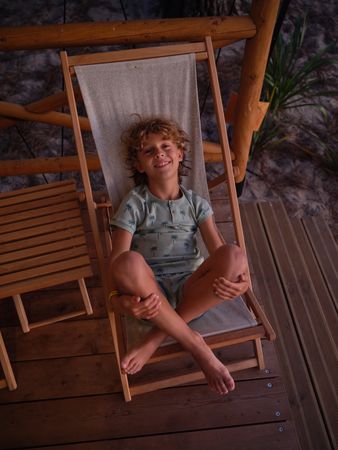 Cheerful boy sitting on deckchair