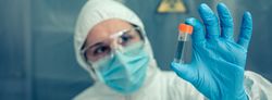 Scientist with protection suit looking vial in the laboratory