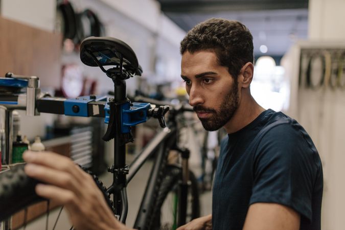 Worker in bike shop concentrating on fixing a bike