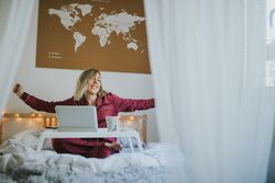 Woman stretching in bed with laptop