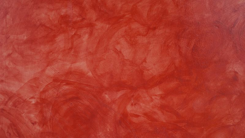 Red painted wall with artistic smudge texture and visible brush strokes