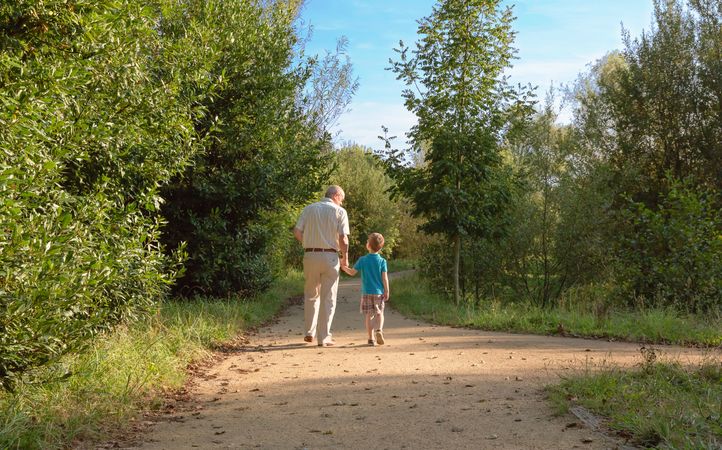 Back of grandfather and grandchild walking outdoors